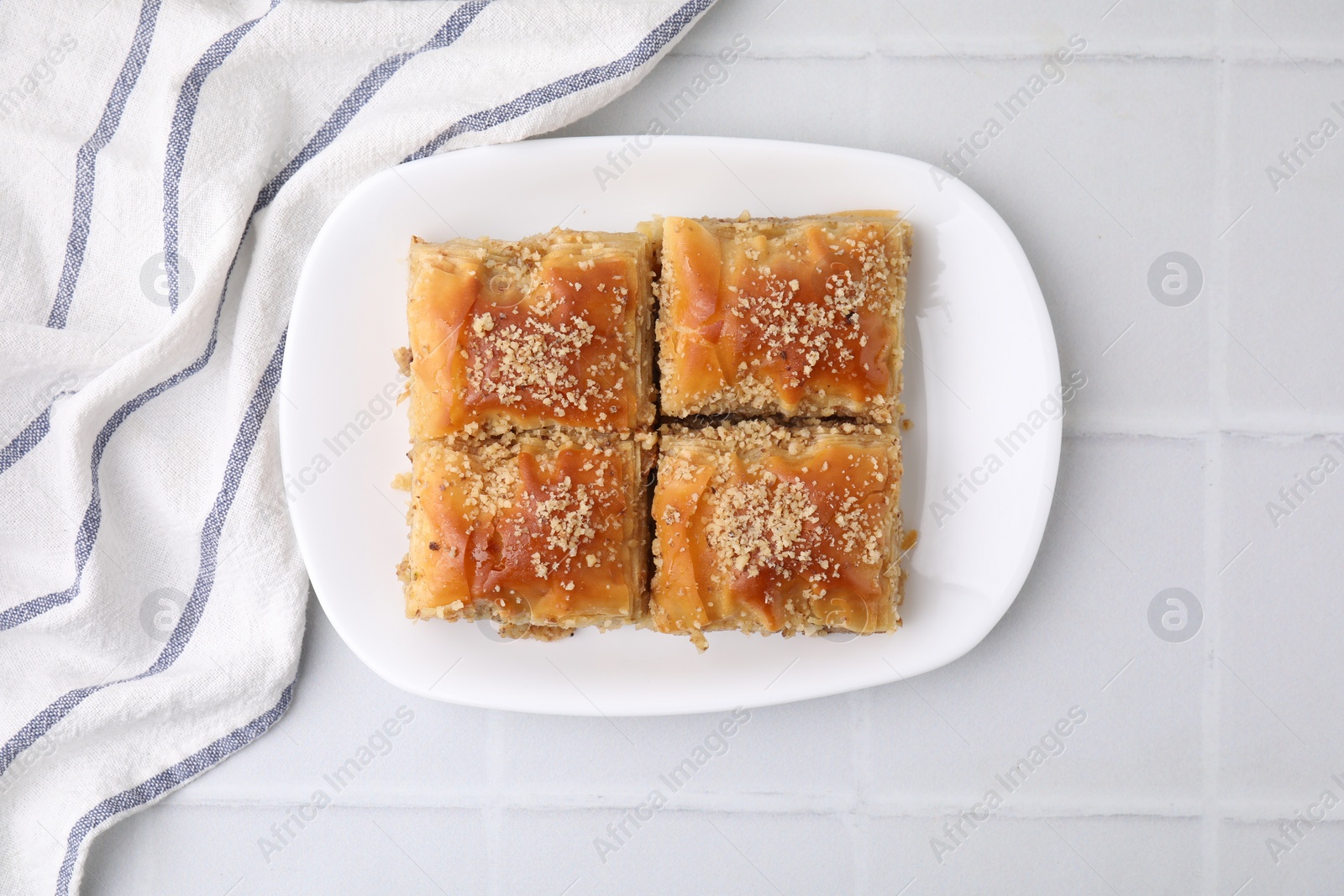 Photo of Eastern sweets. Pieces of tasty baklava on white tiled table, top view