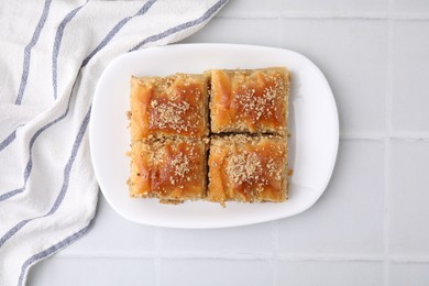 Photo of Eastern sweets. Pieces of tasty baklava on white tiled table, top view