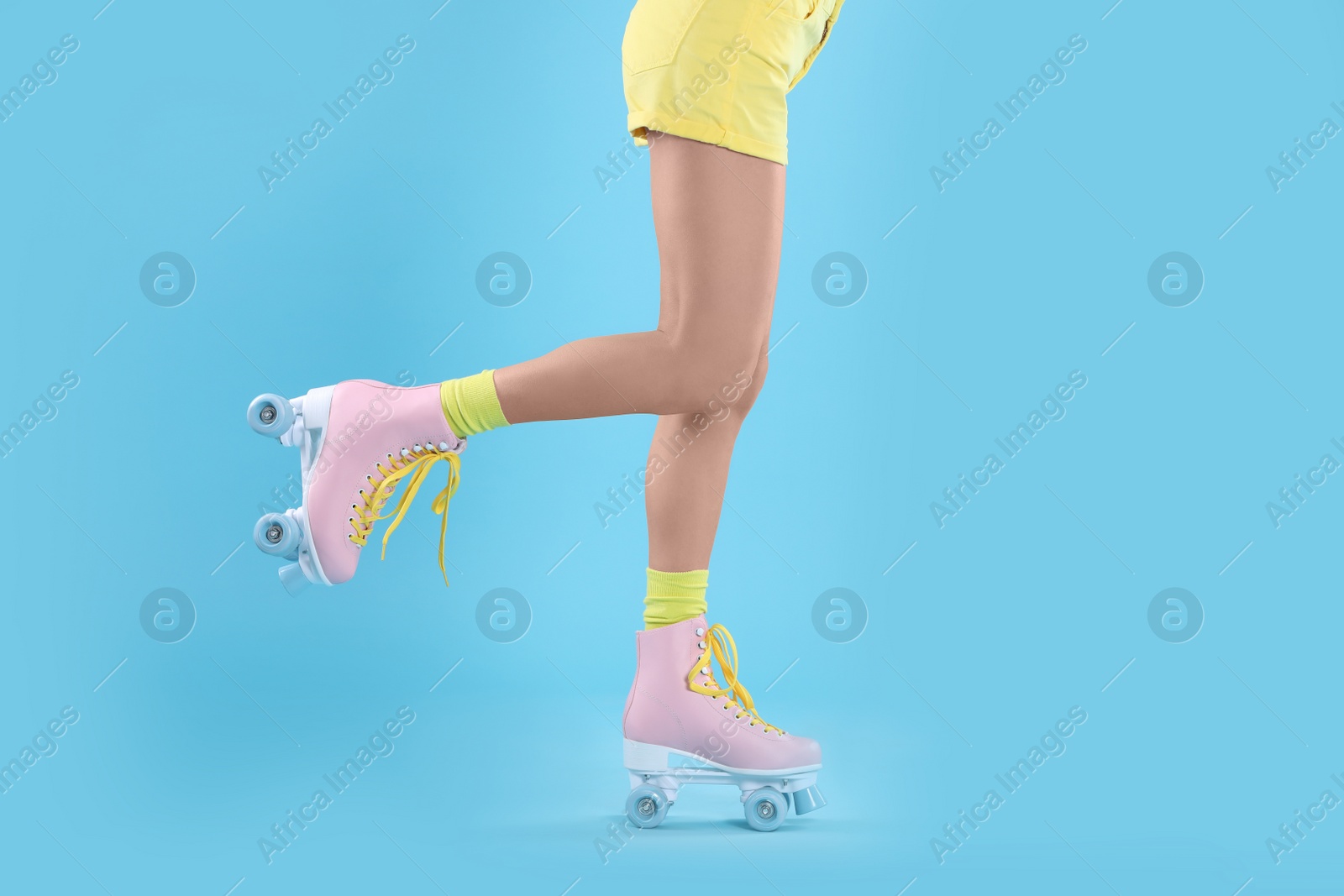 Photo of Young woman with retro roller skates on color background, closeup