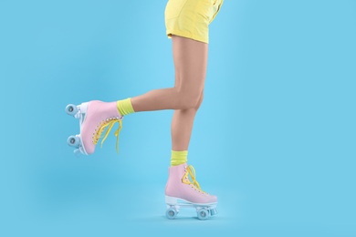 Photo of Young woman with retro roller skates on color background, closeup