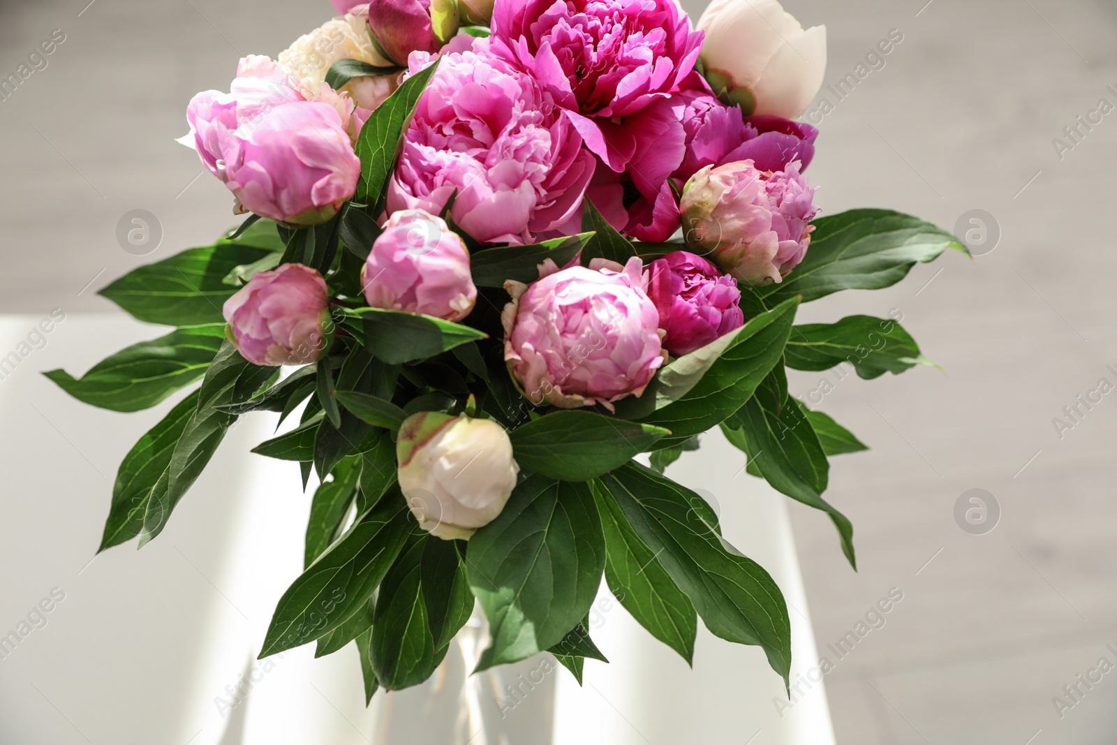 Photo of Vase with bouquet of beautiful peonies on table in room, above view