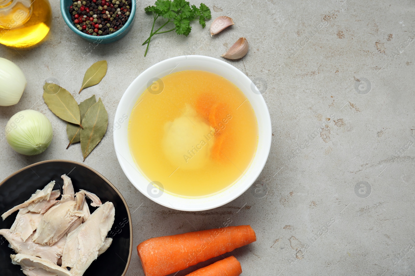 Photo of Delicious chicken bouillon and ingredients on light grey textured table, flat lay. Space for text