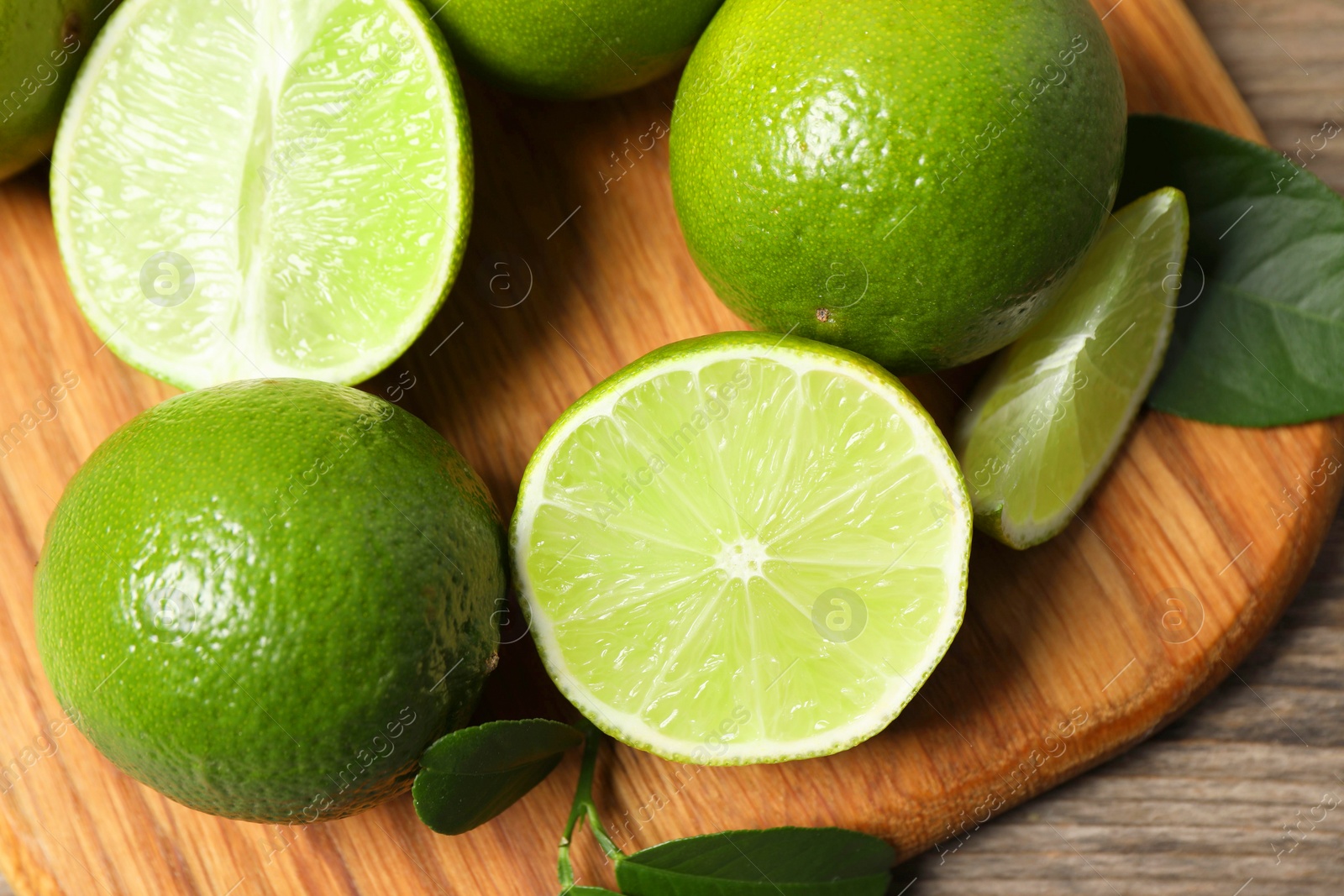 Photo of Fresh ripe limes on wooden table, top view