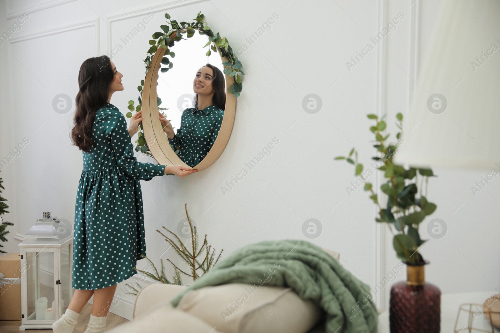 Photo of Woman decorating mirror with eucalyptus branches at home