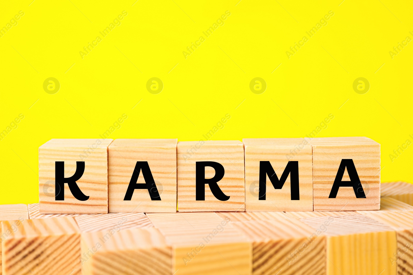 Photo of Word Karma made of cubes with letters on yellow background