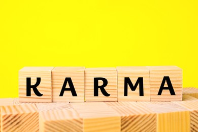 Photo of Word Karma made of cubes with letters on yellow background