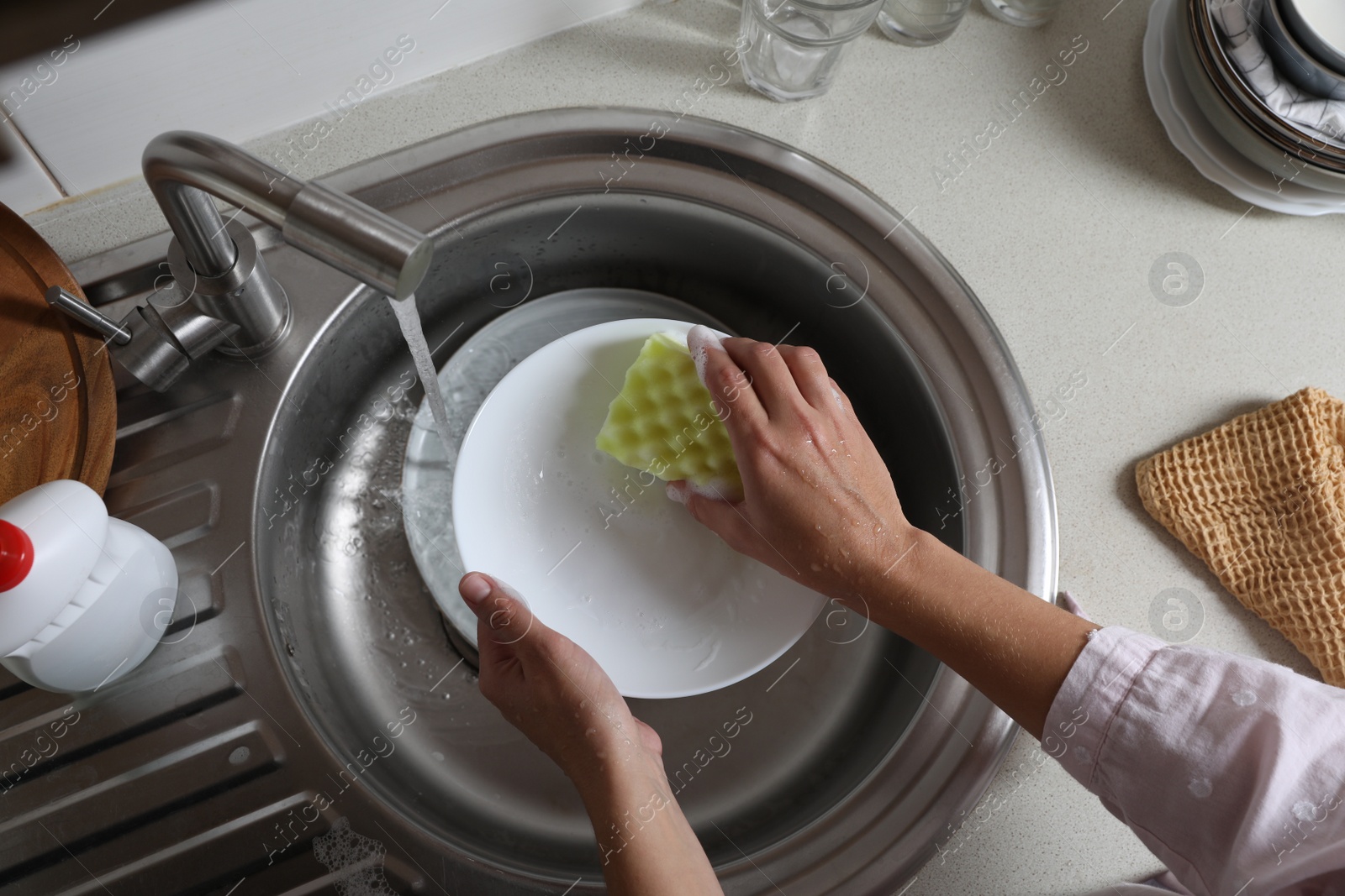 Photo of Woman washing plate in kitchen sink, above view