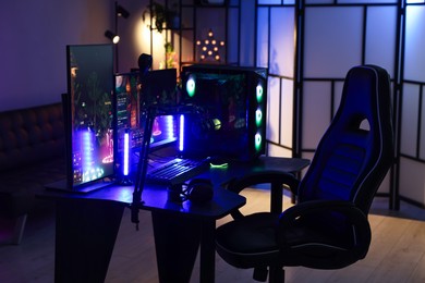 Photo of Playing video games. Stylish room interior with modern computer and gaming chair in neon lights