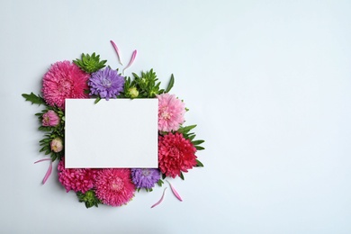 Beautiful aster flowers with sheet of paper on white background, top view. Space for text