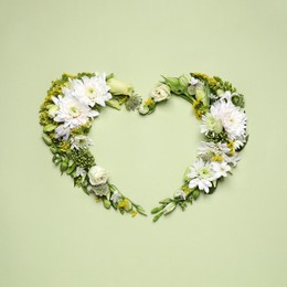 Beautiful heart shaped floral composition on light green background, flat lay