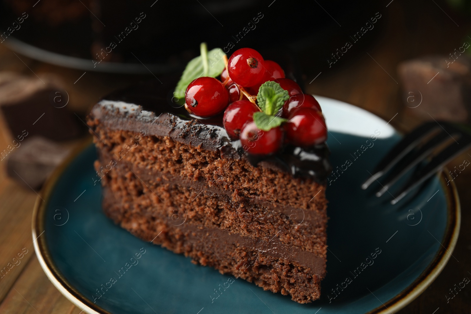 Photo of Piece of tasty homemade chocolate cake with berries and mint on plate, closeup