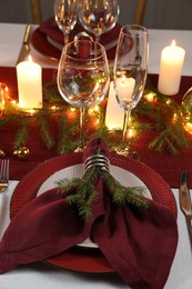 Photo of Christmas table setting with burning candles and festive decor