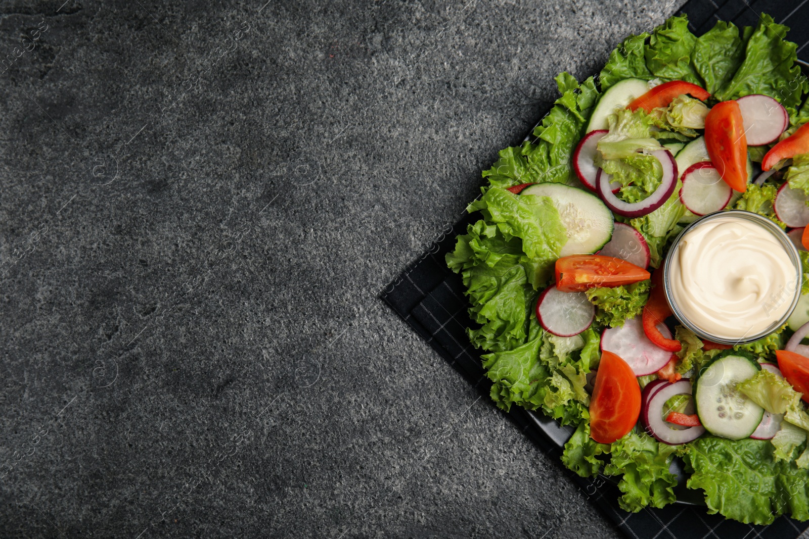Photo of Plate of delicious vegetable salad with mayonnaise on grey table, top view. Space for text