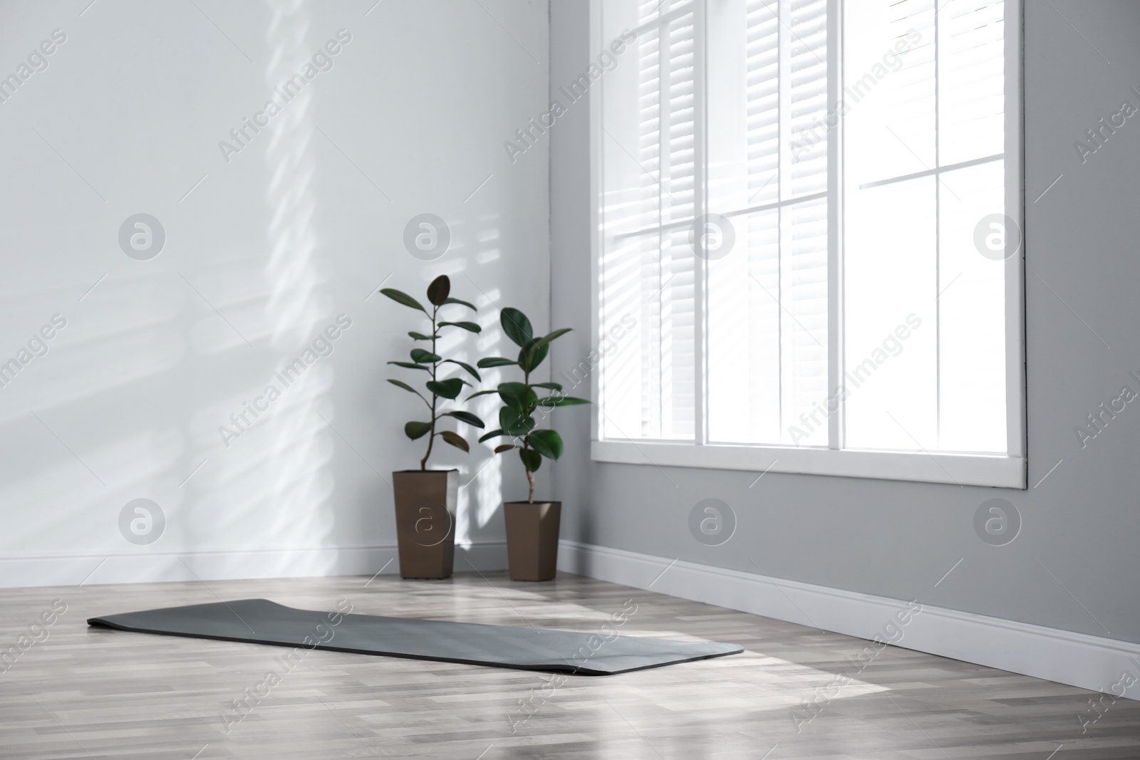 Photo of Unrolled grey yoga mat on floor in room