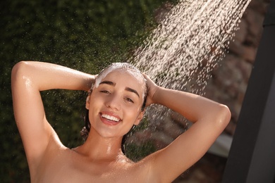 Woman washing hair in outdoor shower on summer day