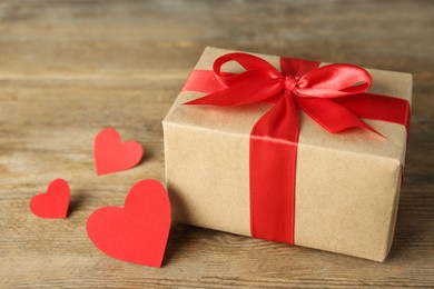 Photo of Beautiful gift box with red hearts on wooden table, closeup