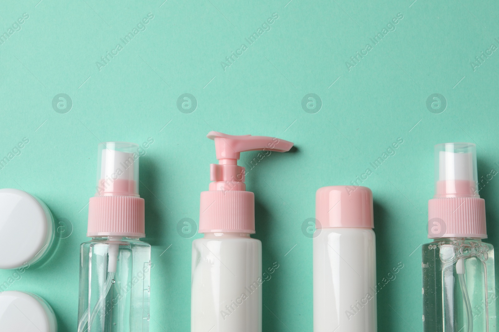 Photo of Cosmetic travel kit on turquoise background, flat lay. Space for text