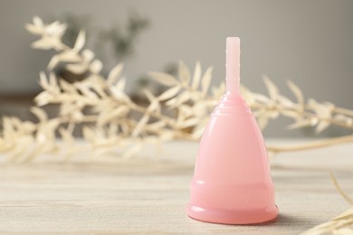 Photo of Pink menstrual cup on wooden table, closeup. Space for text