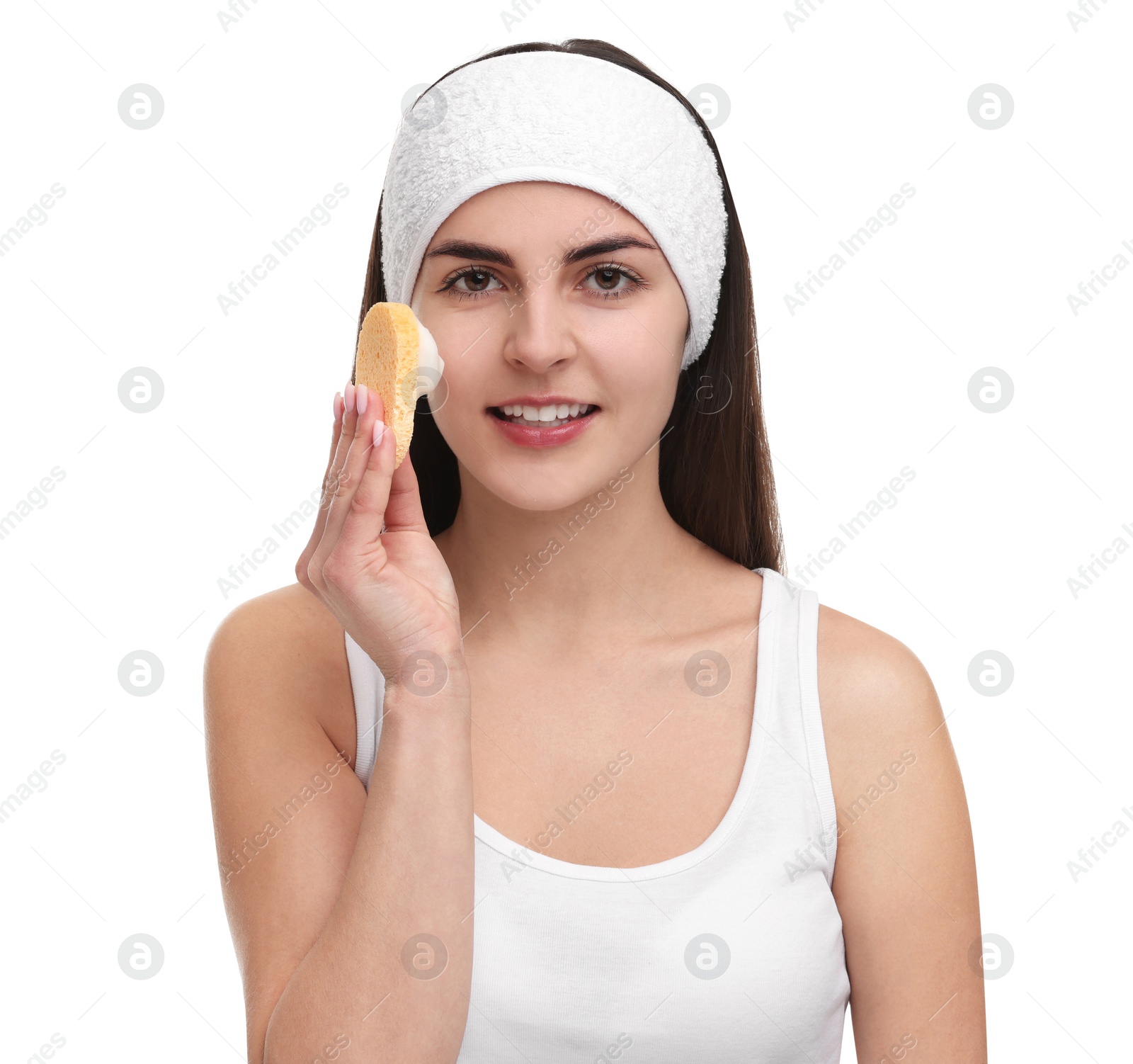 Photo of Young woman with headband washing her face using sponge on white background