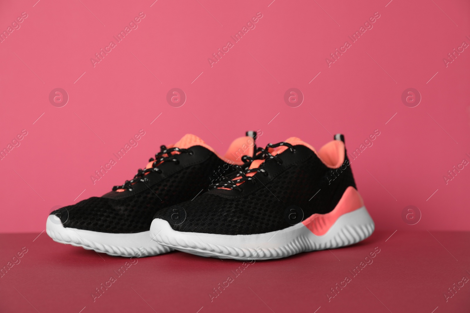 Photo of Pair of stylish sport shoes on pink background