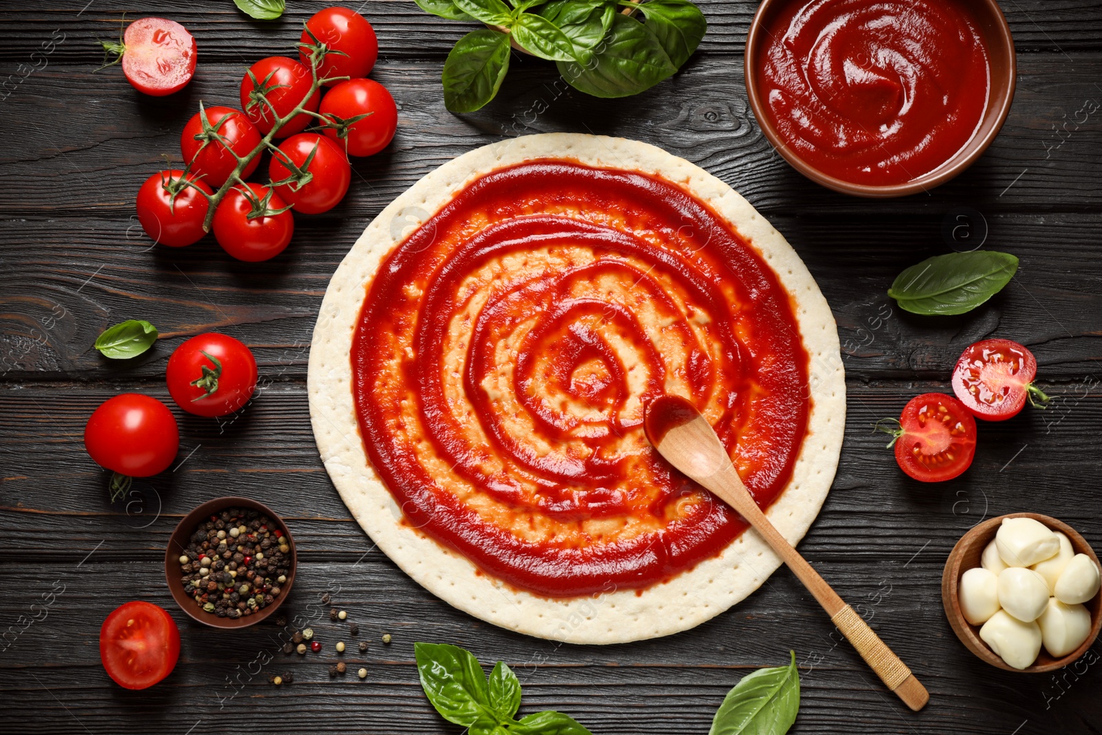 Photo of Flat lay composition with pizza crust and ingredients on dark wooden table