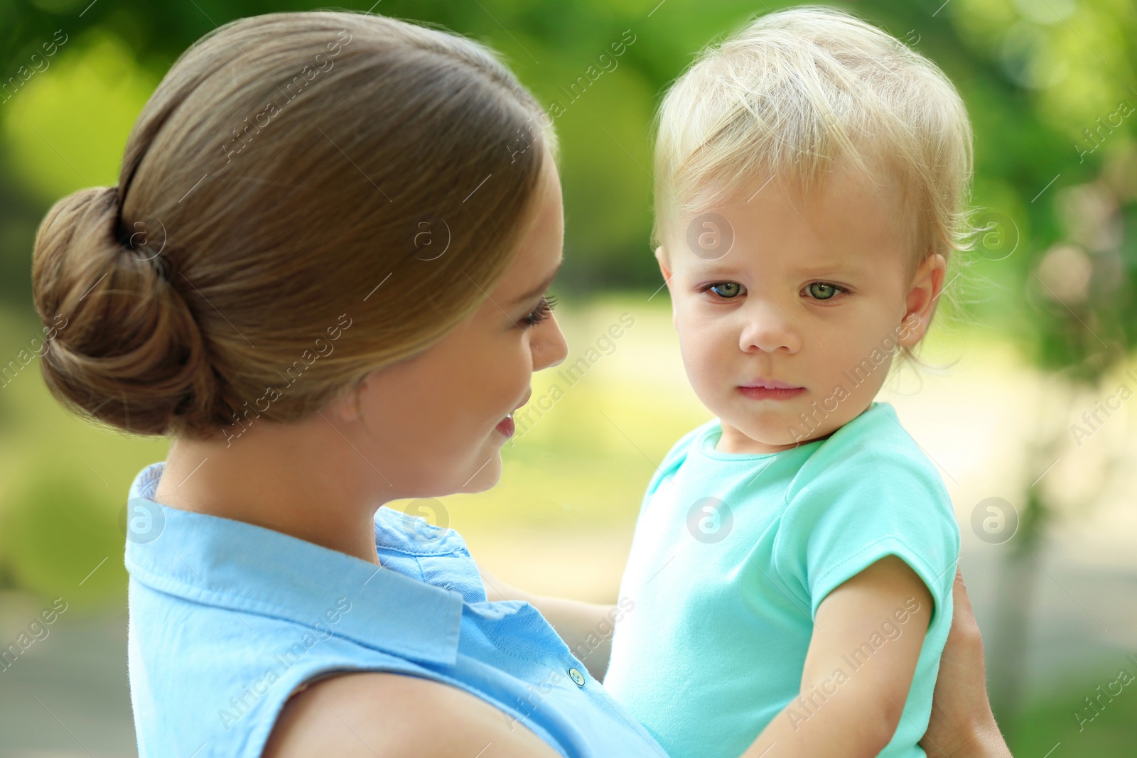 Photo of Young mother with her cute child in green park