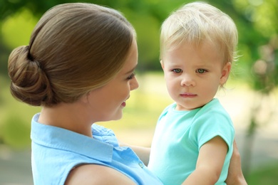 Photo of Young mother with her cute child in green park