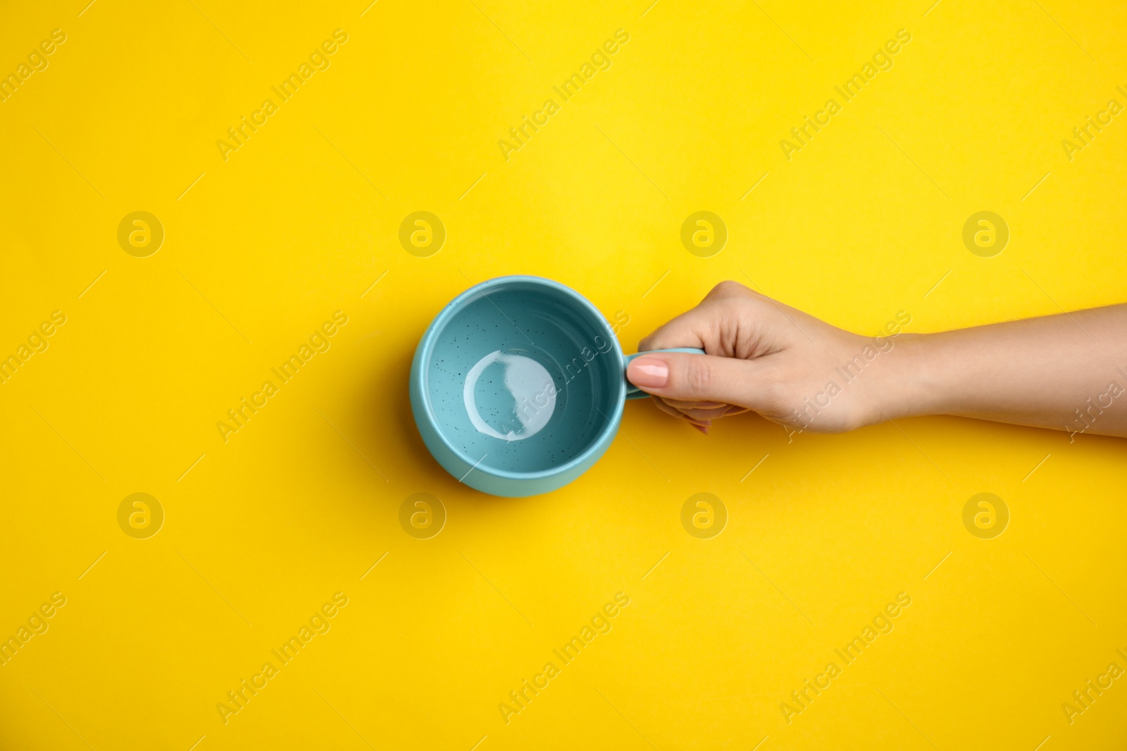 Photo of Woman with empty cup on yellow background, top view