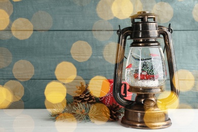 Snow globe in vintage lantern, gift box and Christmas decor on white table, space for text. Bokeh effect