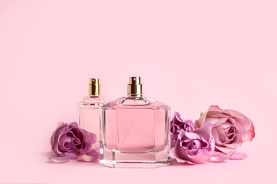Photo of Bottles of perfume and beautiful roses on pink background