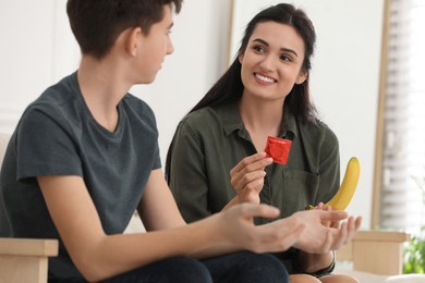 Photo of Mother talking with her teenage son about contraception at home. Sex education concept