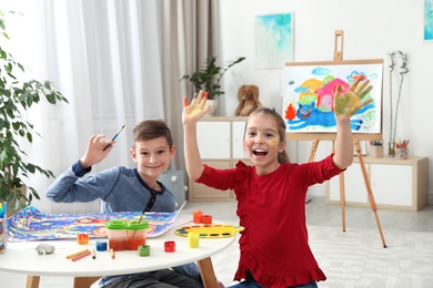 Happy children having fun with paints together at table indoors