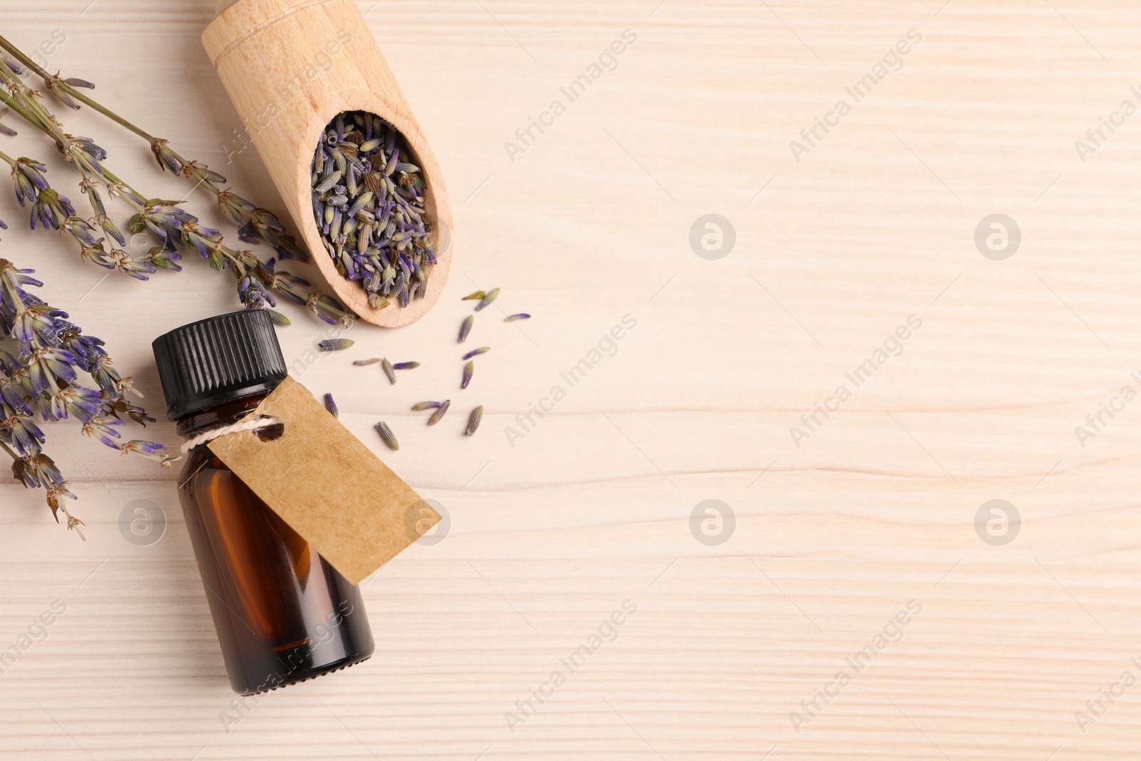 Photo of Bottle of essential oil and lavender flowers on white wooden table, flat lay. Space for text