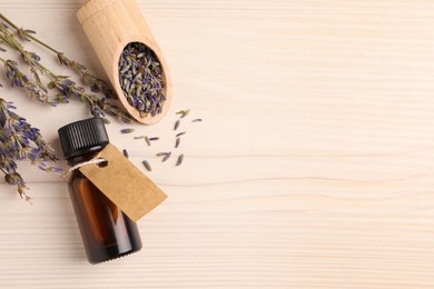 Bottle of essential oil and lavender flowers on white wooden table, flat lay. Space for text