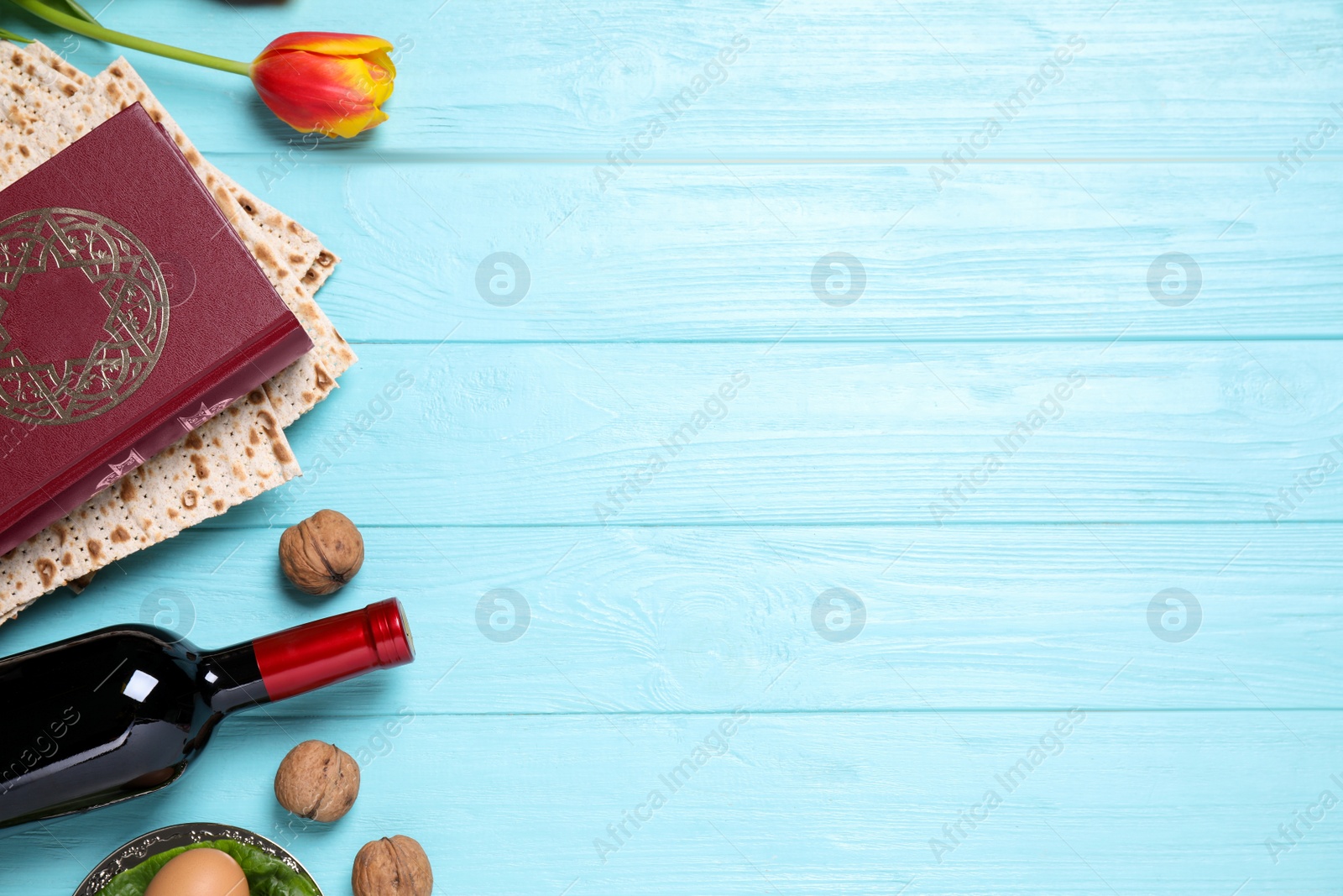 Photo of Flat lay composition with symbolic Pesach (Passover Seder) items on light blue wooden table, space for text