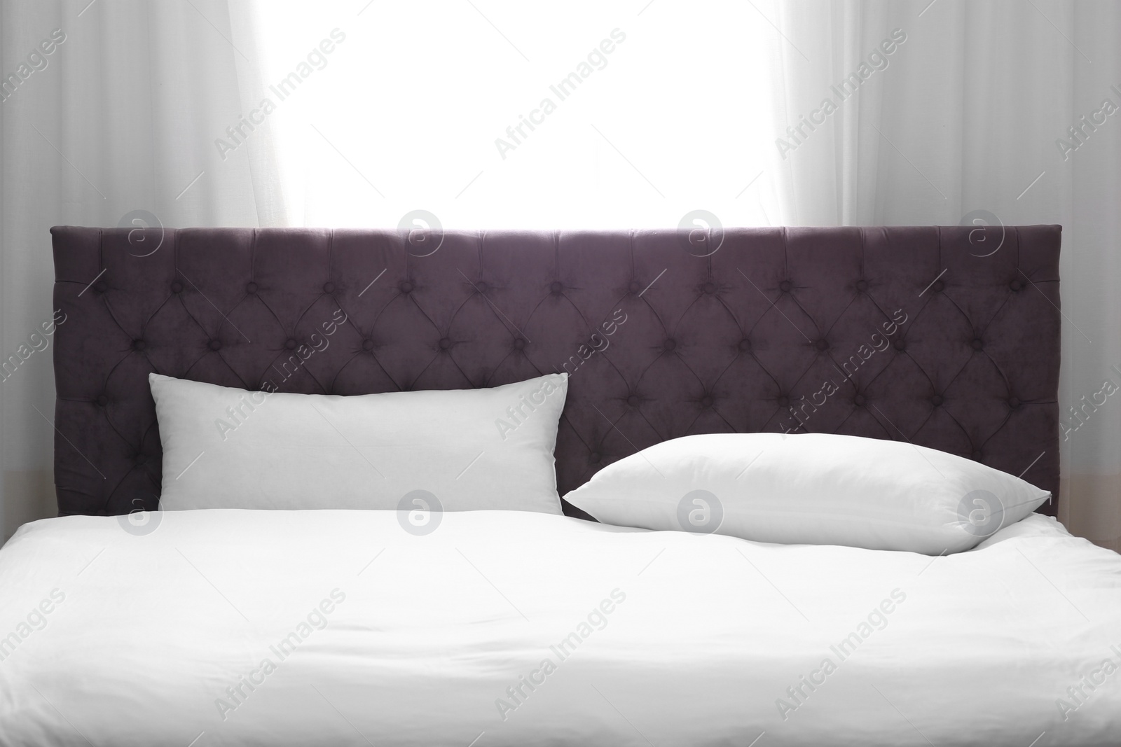 Photo of Modern bed with soft pillows near window