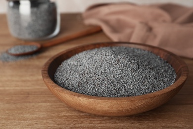 Photo of Poppy seeds in plate on wooden table