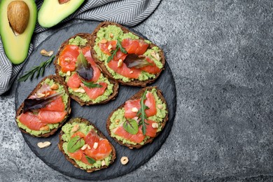 Photo of Delicious sandwiches with salmon, avocado and herbs on grey table, flat lay. Space for text