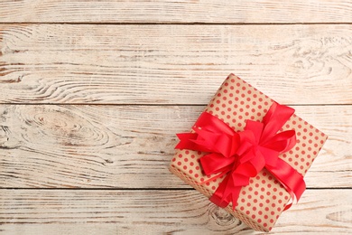 Elegant gift box with bow on wooden background, top view