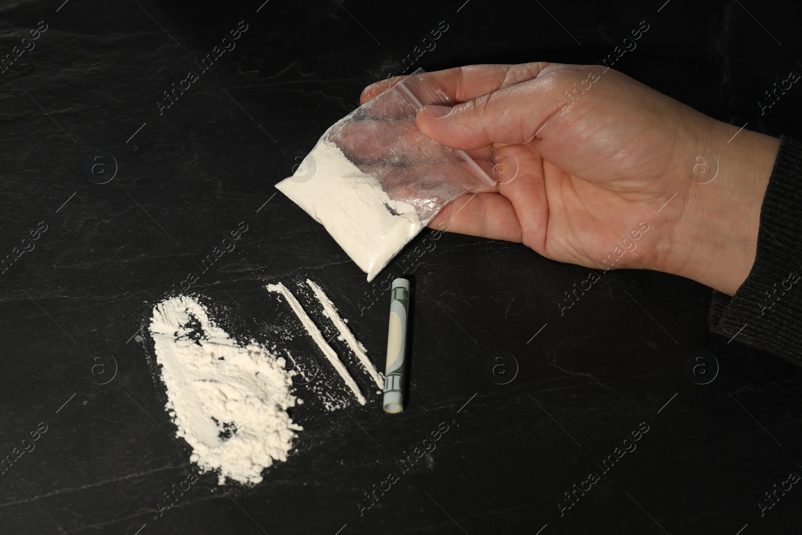 Photo of Drug addiction. Man with cocaine and rolled dollar banknote at dark textured table, closeup