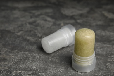 Photo of Natural crystal alum deodorants on grey table. Space for text