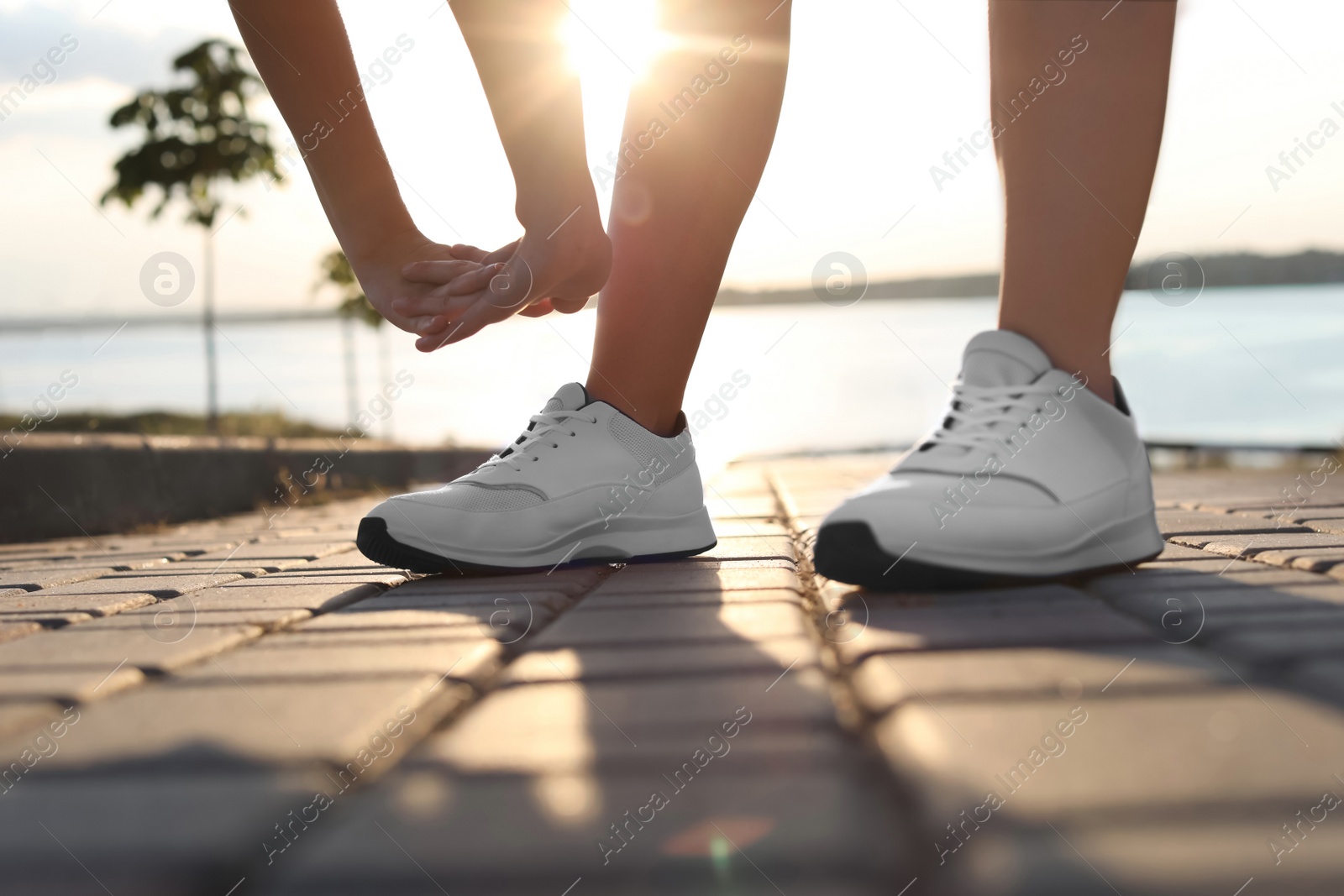 Photo of Young woman stretching near river in morning, closeup