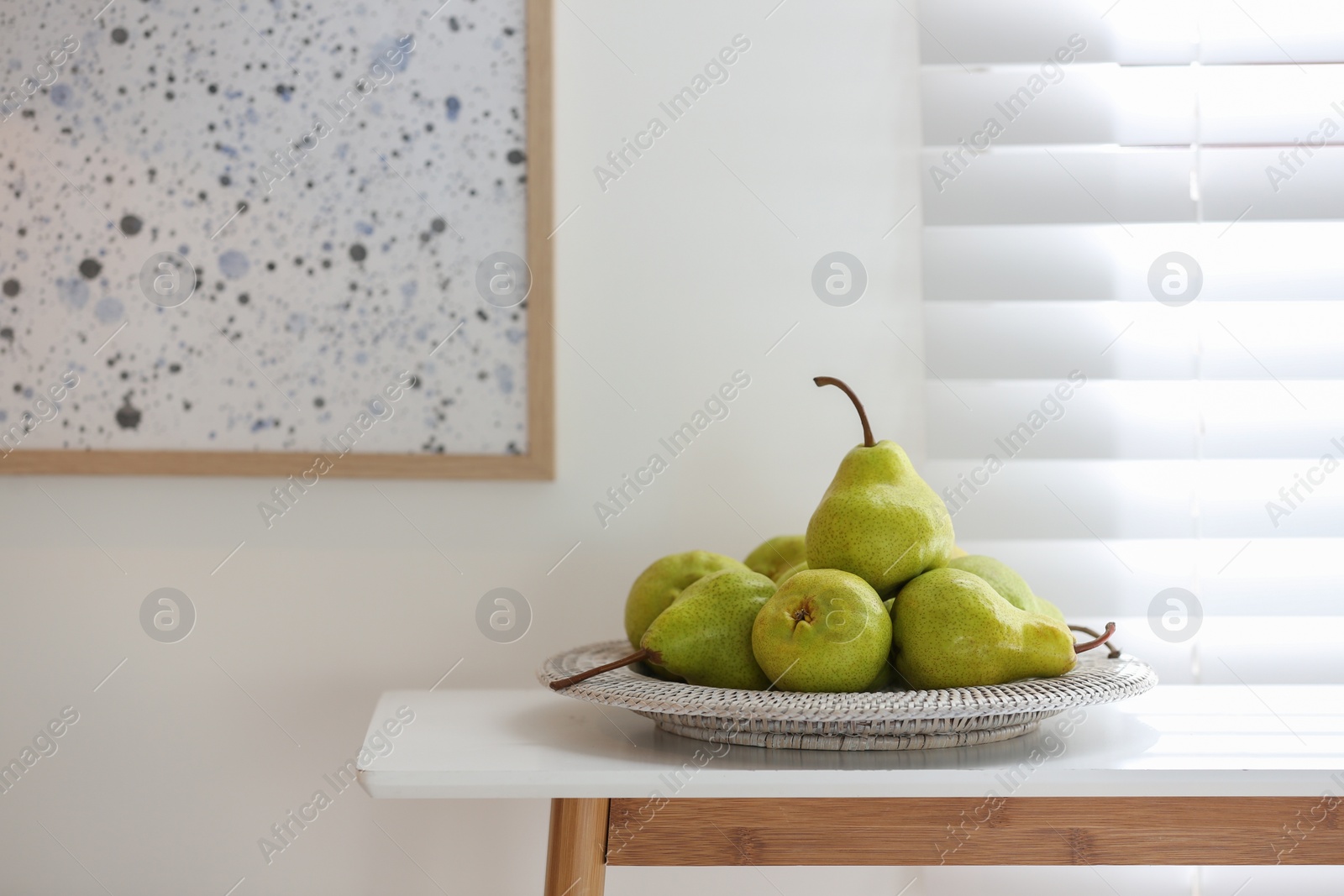 Photo of Fresh ripe pears on white table in room. Space for text