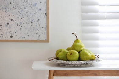 Photo of Fresh ripe pears on white table in room. Space for text