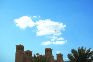 Photo of Distant view of airplane in sky over tropical resort