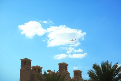 Distant view of airplane in sky over tropical resort