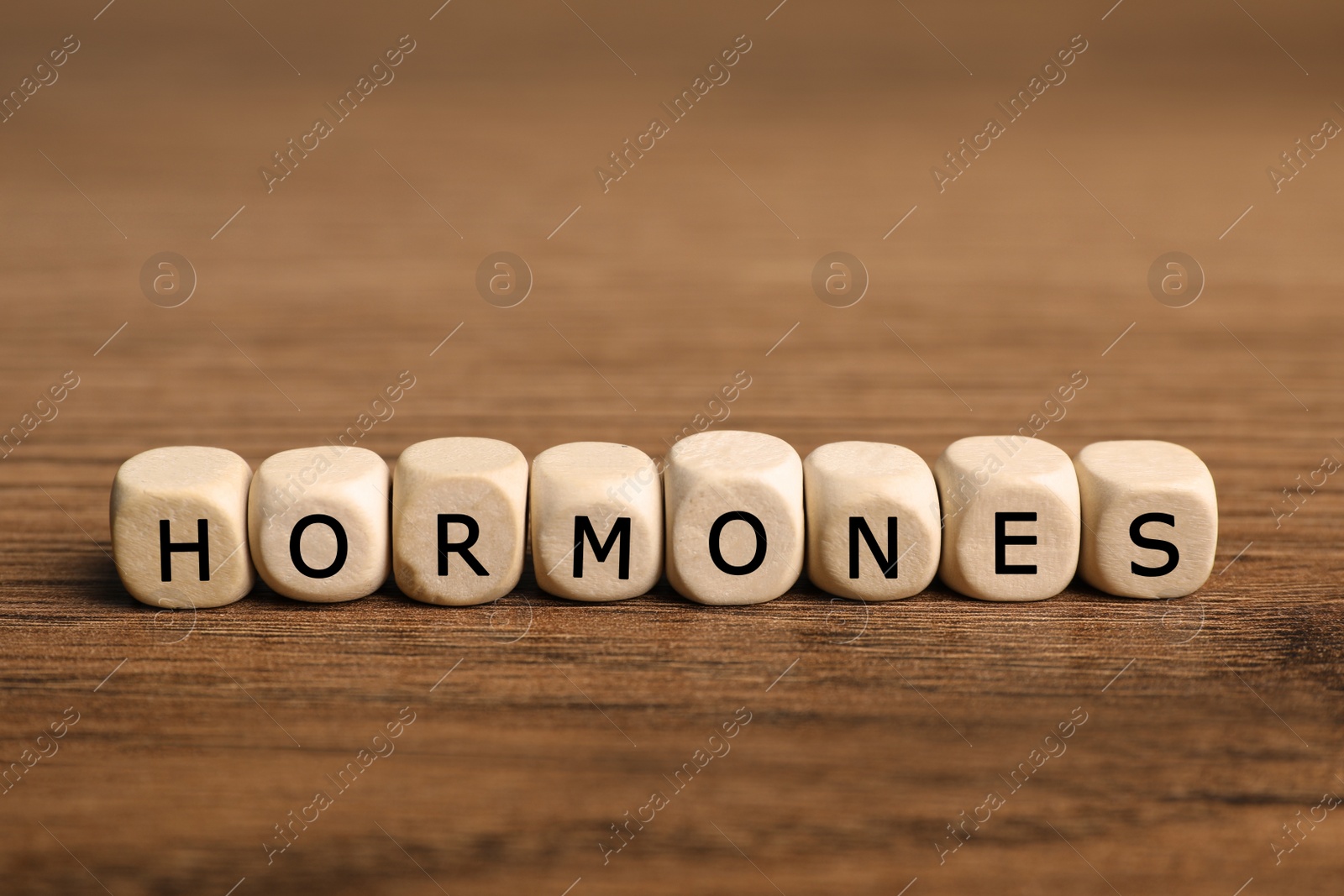 Photo of Word Hormones made of small cubes with letters on wooden table