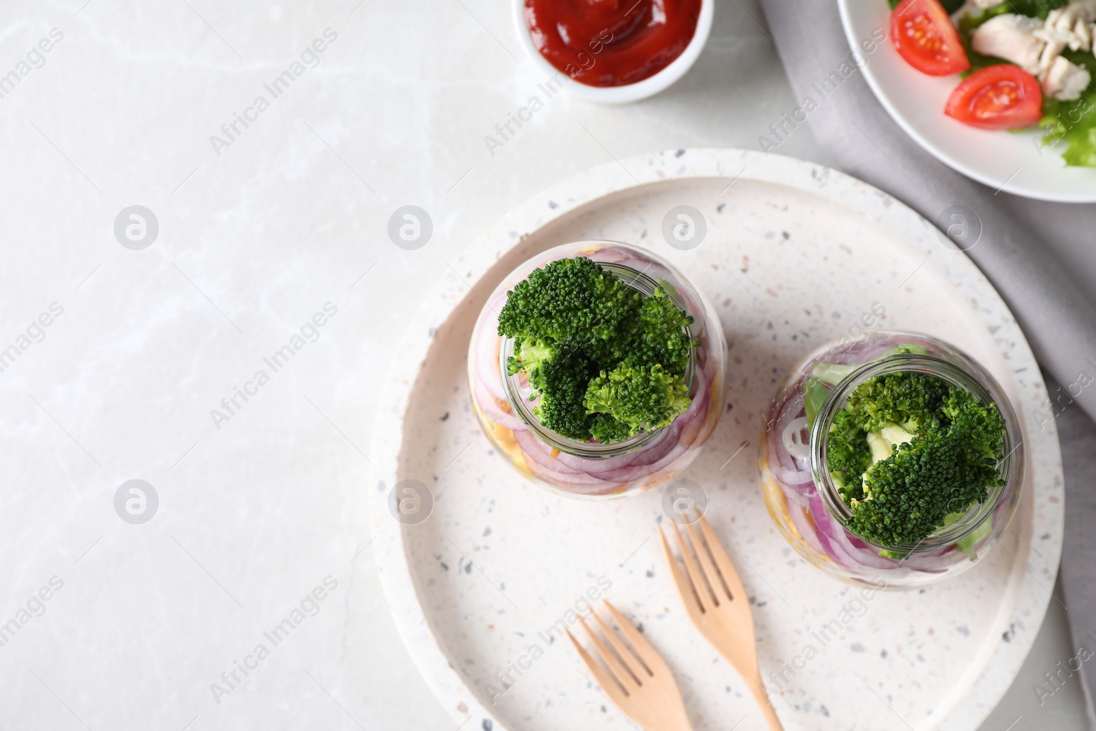 Photo of Healthy salad in glass jars on light table, flat lay