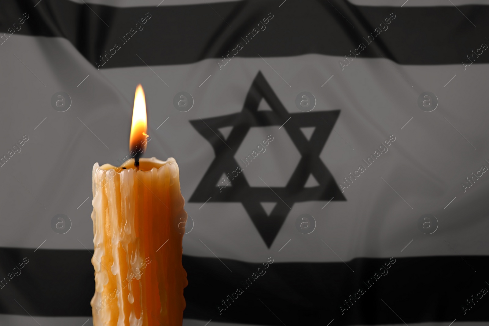 Image of Burning candle against flag of Israel, closeup