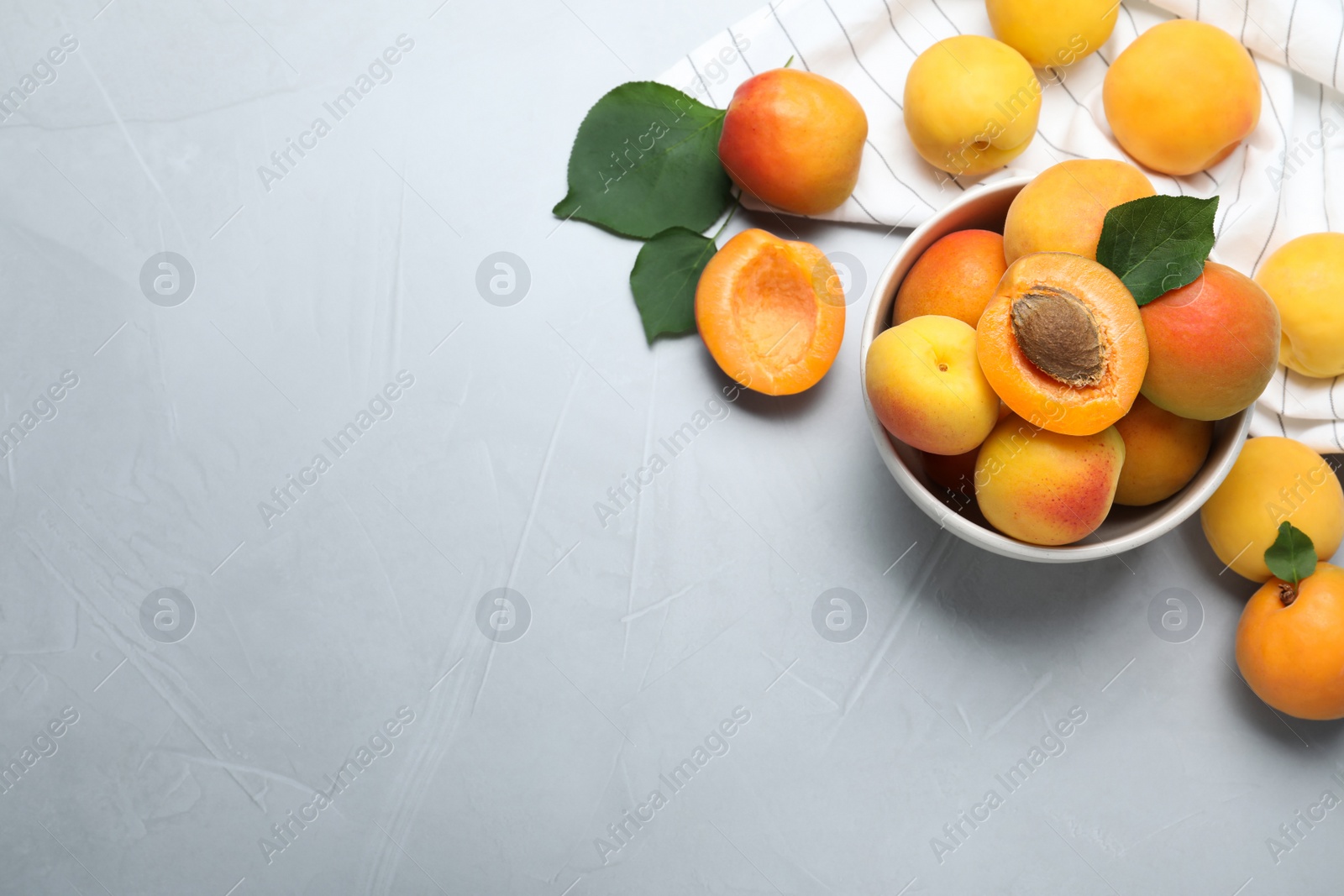 Photo of Many fresh ripe apricots on light grey table, flat lay. Space for text